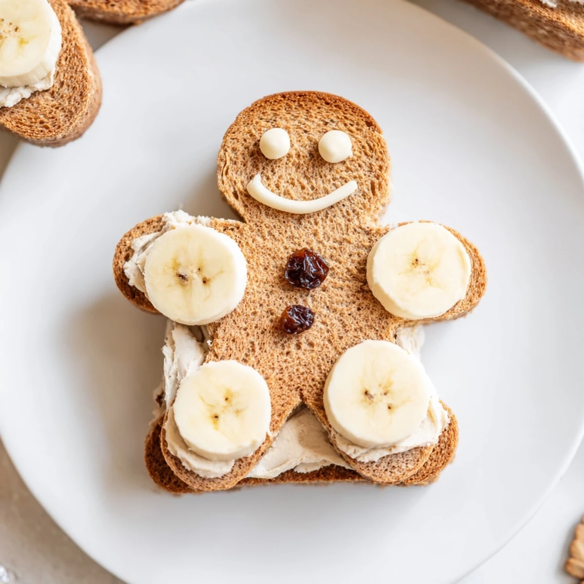 Gingerbread man sandwich cutouts with cream cheese filling, decorated with apple slices and raisins.