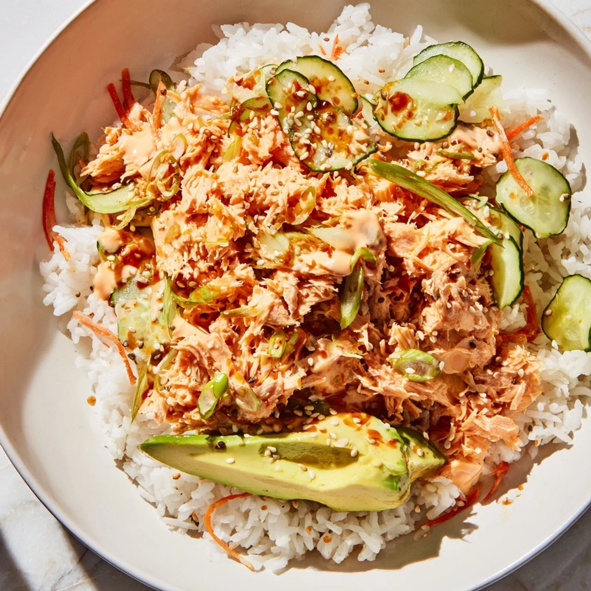 A close-up of a Spicy Canned Salmon Rice Bowl, with vibrant veggies and creamy sriracha mayo.