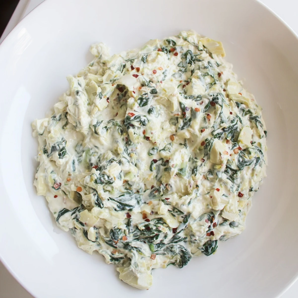 A warm bowl of spinach artichoke dip, ready to be scooped up and enjoyed as an appetizer.