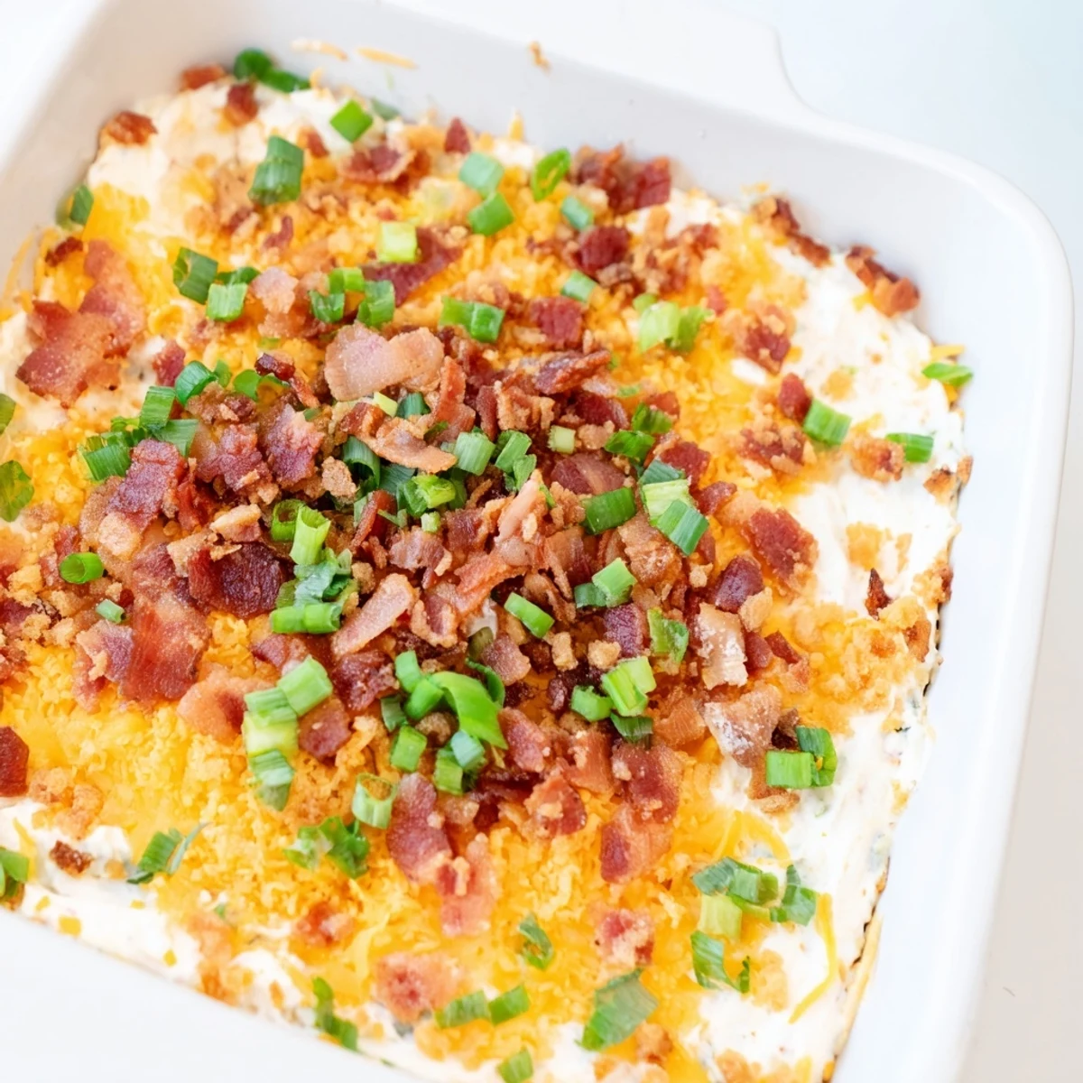 Warm, bubbly Cheesy Bacon Ranch Dip, topped with crispy bacon, ready for your next party.