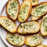 Golden vodka butter crostini slices with a subtle lemon zest and chive garnish on a rustic wooden board.
