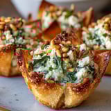 Mediterranean spinach and feta crisps served warm on a platter with lemon wedges and herbs.