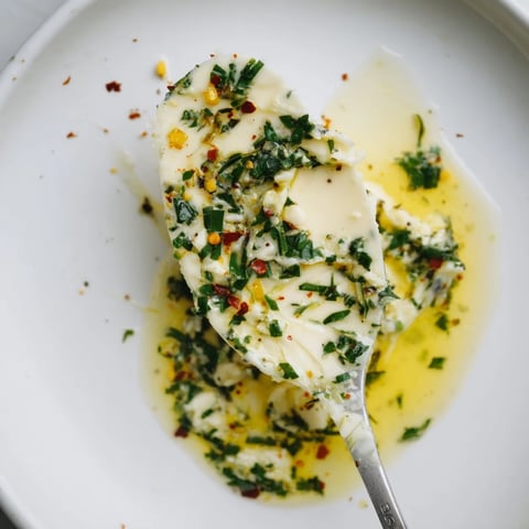A warm bowl of creamy Cowboy Butter Sauce, garnished with fresh parsley and chives, perfect for drizzling over grilled steak.  
