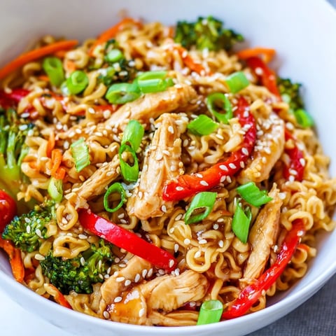A top-down view of Spicy Ramen Stir-Fry featuring tender chicken, crisp broccoli, and red bell peppers glistening in a savory, glossy sauce.
