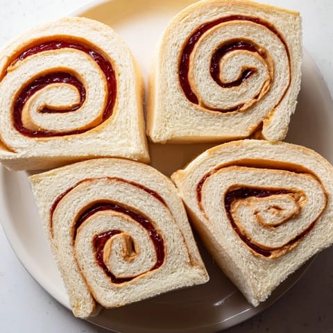 Fresh, quartered PB&J pinwheel rolls show a fun way to enjoy a peanut butter and jelly sandwich.