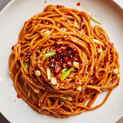 Close-up of freshly made Garlic Chili Oil Noodles, glistening with chili oil and fragrant spices.