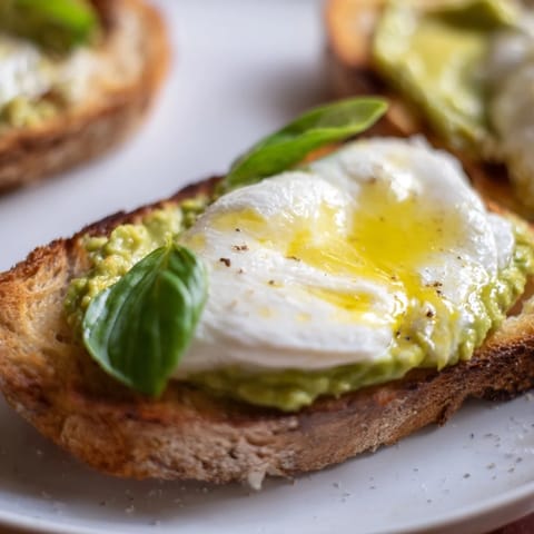 Perfectly melted mozzarella bubbles over creamy avocado on crisp toast, served warm with a drizzle of olive oil.