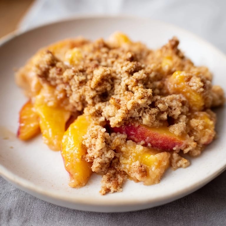 A close-up of a rustic, buttery Peach and Ginger Crumble, perfect for a cozy afternoon treat.