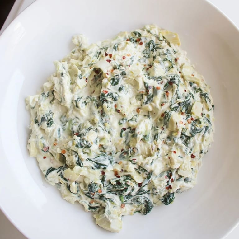 A warm bowl of spinach artichoke dip, ready to be scooped up and enjoyed as an appetizer.