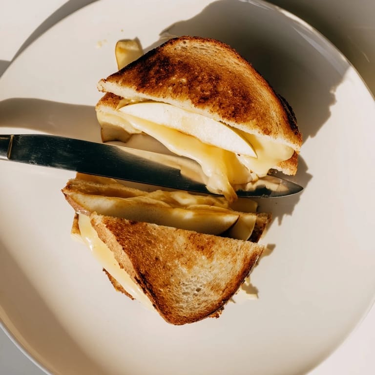 Smoked Gouda & Apple Grilled Cheese sandwiches cut diagonally, revealing melted cheese, crisp apple slices, and buttery toasted bread.